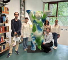 Gemeinsames Gruppenfoto in der Bibliothek der Evangelischen Hochschule Berlin: Das Bild zeigt die ukrainischen Projektpartnerinnen des TRACE-Projekts gemeinsam mit EHB-Kolleg:innen in der EHB-Bibliothek vor dem Buddy-Bär, dem Maskottchen der Hochschule. Foto: EHB