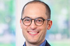 Das Bild zeigt einen freundlich lächelnden Mann mit einer Brille.