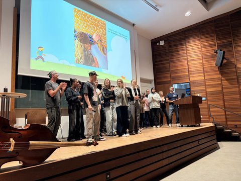 Das Bild zeigt einige Personen auf der Bühne des Audimax die etwas präsentieren.