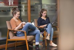 Zwei Personen sitzen auf Sesseln und lesen 