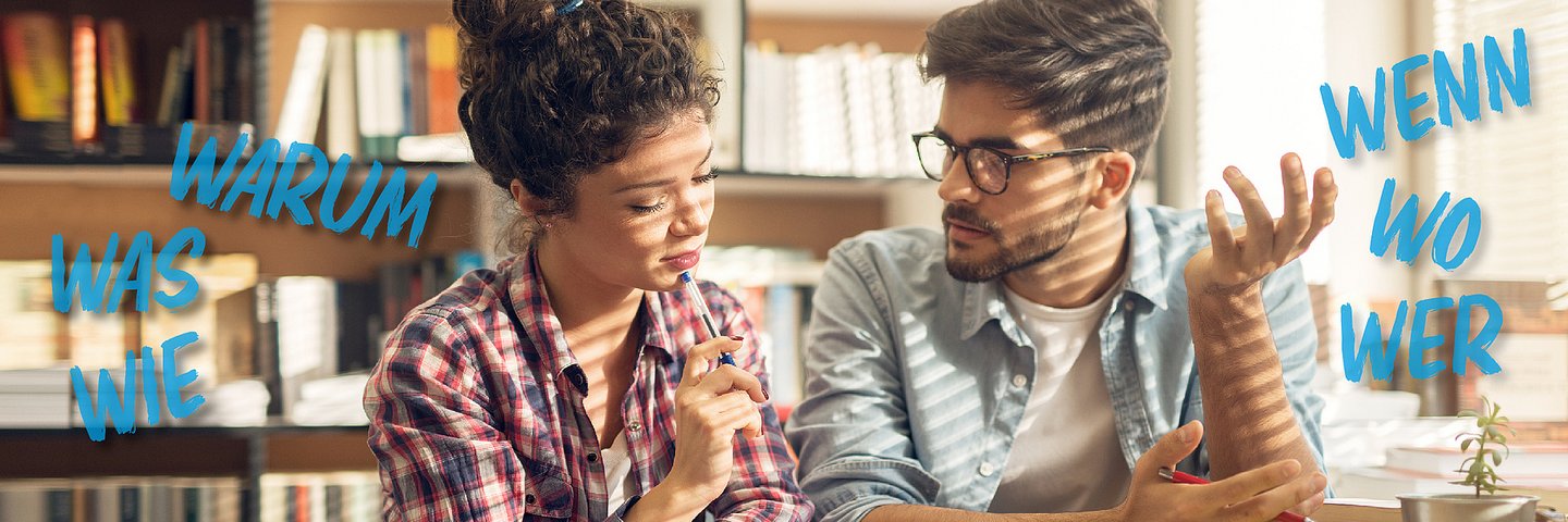 Zwei Personen im Gespräch sitzend vor einer Bücherwand