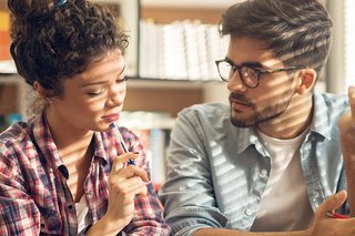 Zwei Personen im Gespräch sitzend vor einer Bücherwand