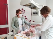 Zwei Hebammen stehen am Neugeborerenbett im SkillsLab