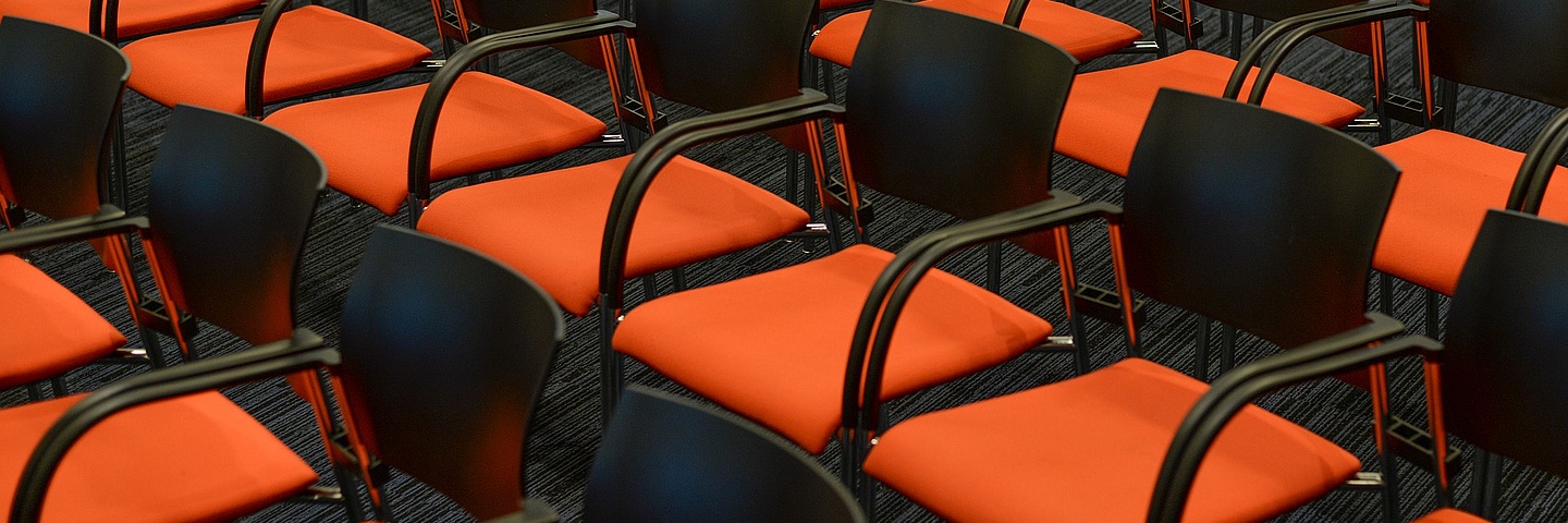 Leere Sitzreihen, orange schwarzer Stühle