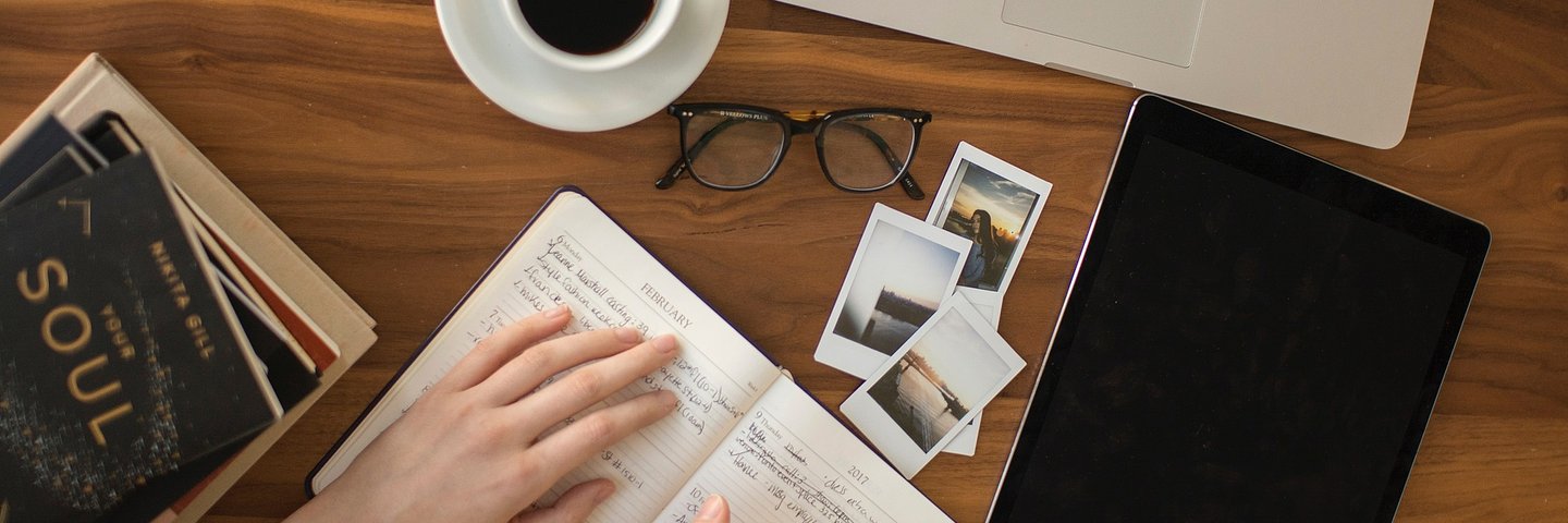 schreibtisch mit Laptop, Kaffeetasse, Brille, Bücher, Tablet