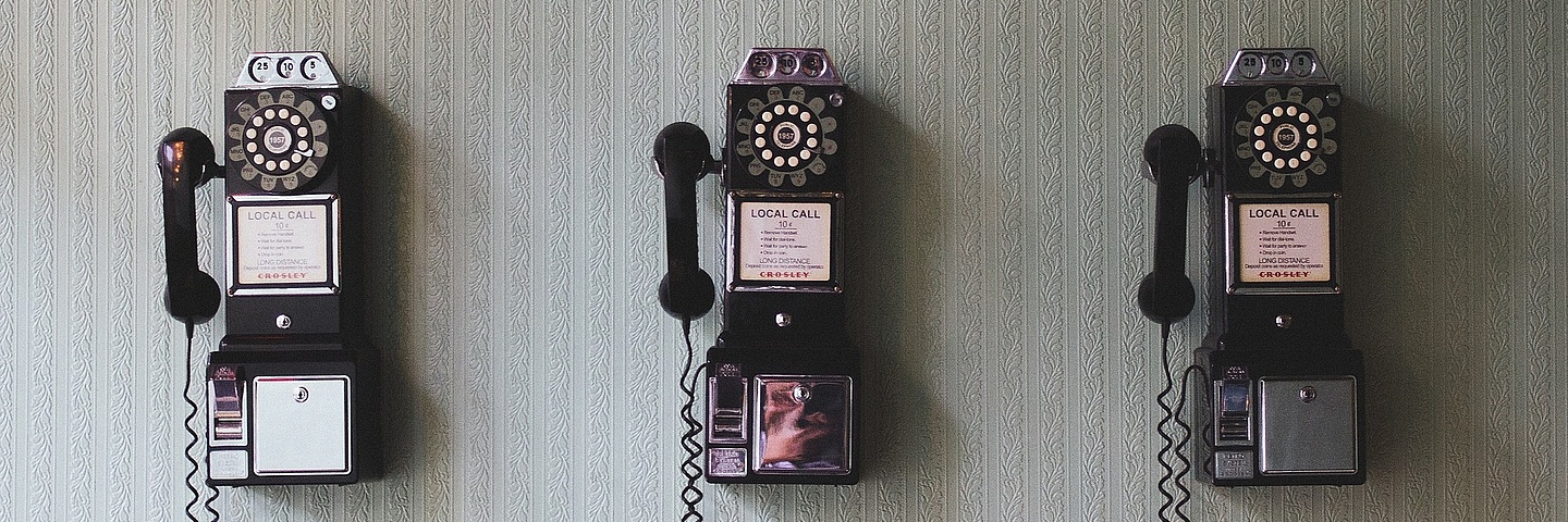 Drei alte Wählscheibentelefone nebeneinander an der Wand