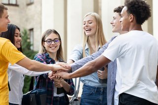 Young students stacking hands together in college campus
