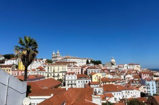 ein tiefblauer Himmel über roten Dächern auf weißen Häusern in Lissabon