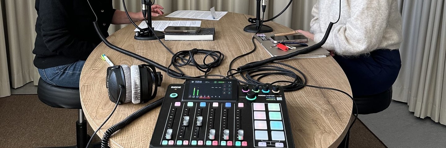 Blick auf eine Podcast-Aufnahmestation mit zwei Personen mit Mikrophonen