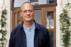 Das Bild zeigt einen Mann mit Brille, der leicht lächelnd in die Kamera blickt.