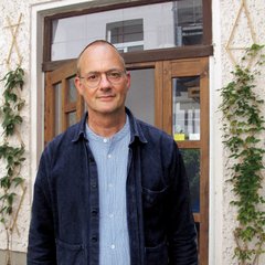 Das Bild zeigt einen Mann mit Brille, der leicht lächelnd in die Kamera blickt.