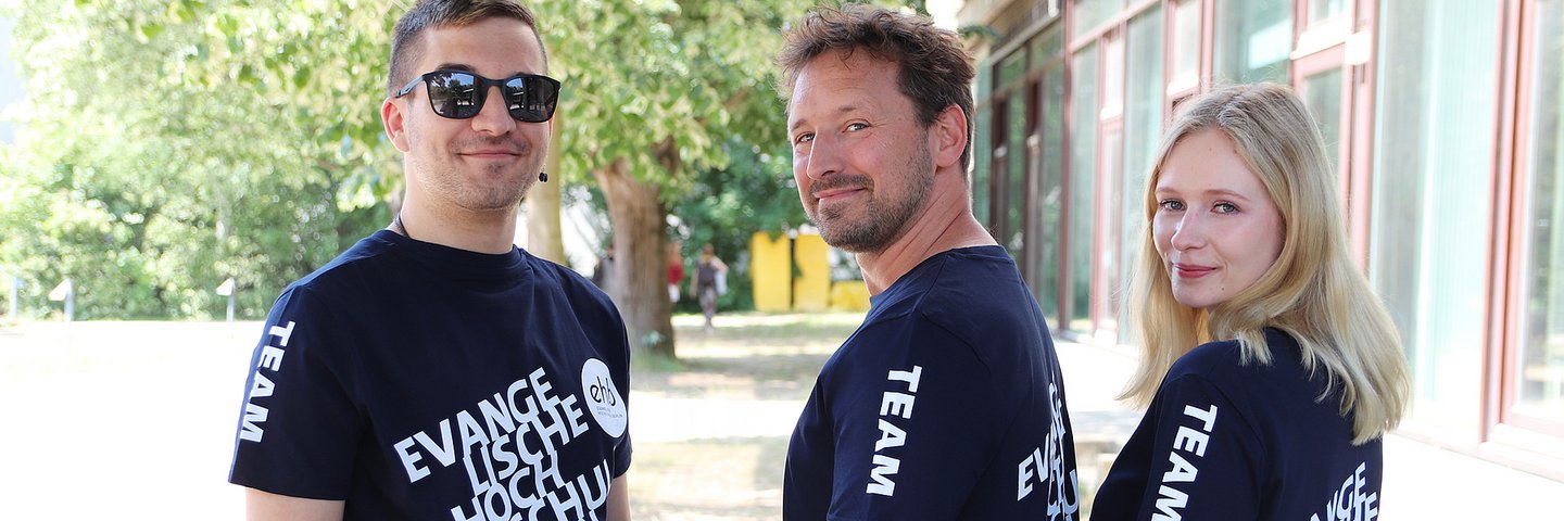 Zwei Männer und eine Frau mit Hochschul T-Shirts auf dem EHB-Campus