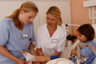 Gesundheitspflegerinnen legen Verband bei einem Kind im Krankenhaus an 