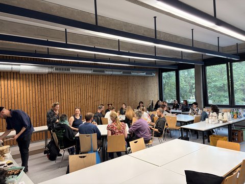 Das Bild zeigt einen Seminarraum in dem eine Gruppe im Kreis zusammen sitzt und etwas zu besprechen scheint.