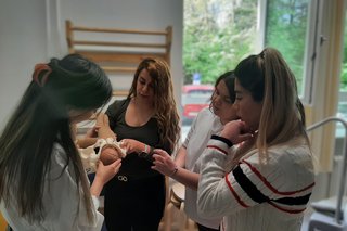 Das Bild zeigt einige Studierende die im Skillslab mithilfe einer Puppe eine Geburt simulieren.