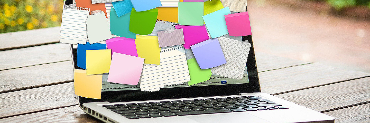 Aufgeklappter Laptop mit vielen bunten Post-its auf dem Bildschirm