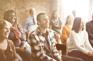 Gruppe von Menschen in Stuhlreihen