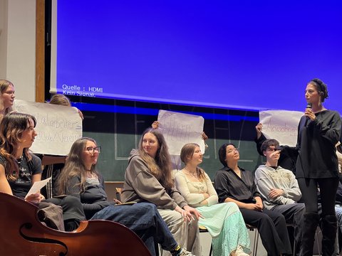 Das Bild zeigt einige Personen auf der Bühne des Audimax die etwas präsentieren.